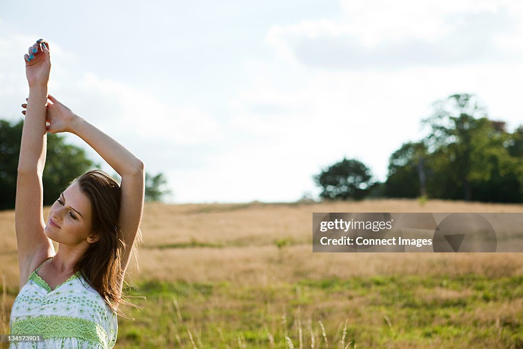 Young woman stretching in a field