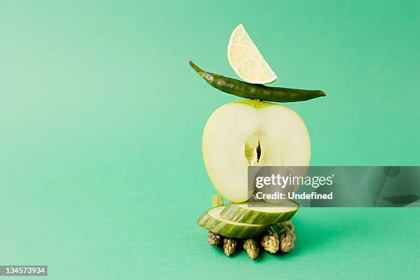 arrangement of apple, asparagus, green chili and cucumber against green background - balance cuisine stock-fotos und bilder