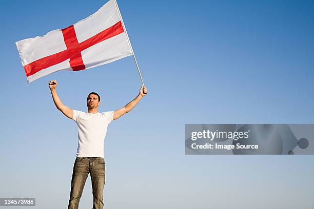 man holding st george's cross flag in the air - waving flags stock pictures, royalty-free photos & images