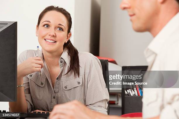 female employee gazing longingly at her male colleague - romance de oficina fotografías e imágenes de stock