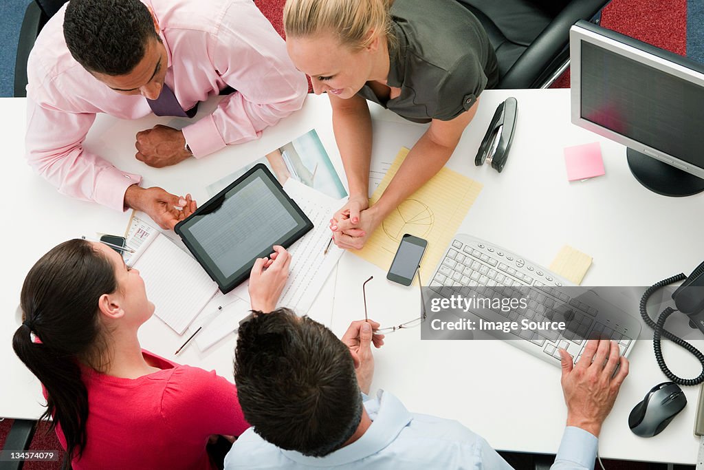 Four employees gathered around a digital tablet