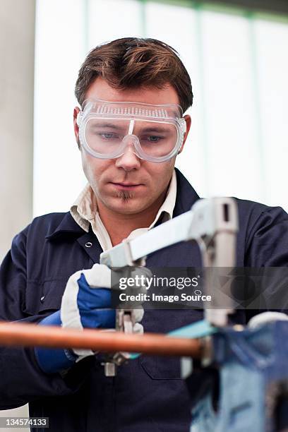 plumber cutting into copper pipe in workshop - sawing stock pictures, royalty-free photos & images