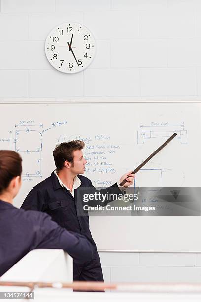 professional plumber teaching apprentice in front of whiteboard - teacher in front of whiteboard stock pictures, royalty-free photos & images