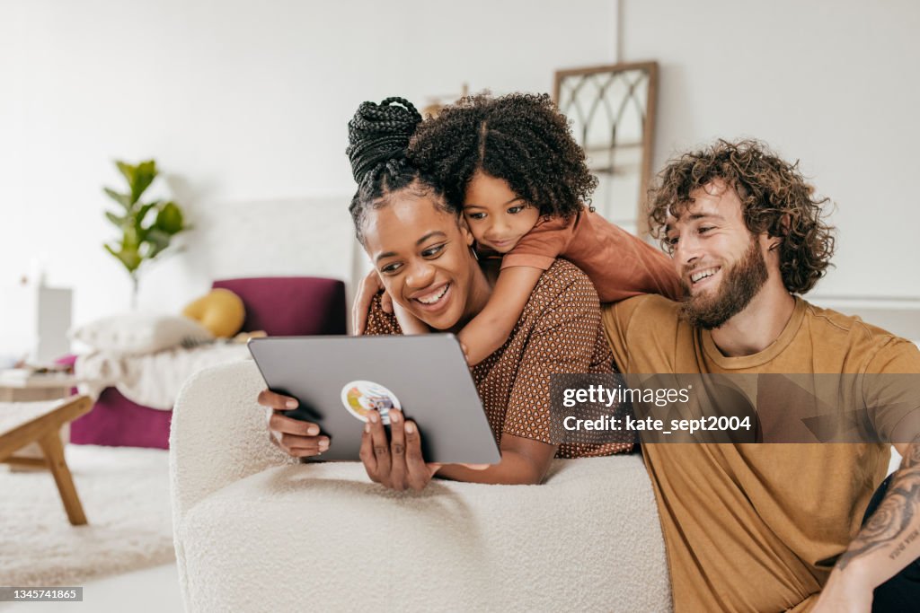 Lächelnde Eltern und Tochter zu Hause beim gemeinsamen Online-Film