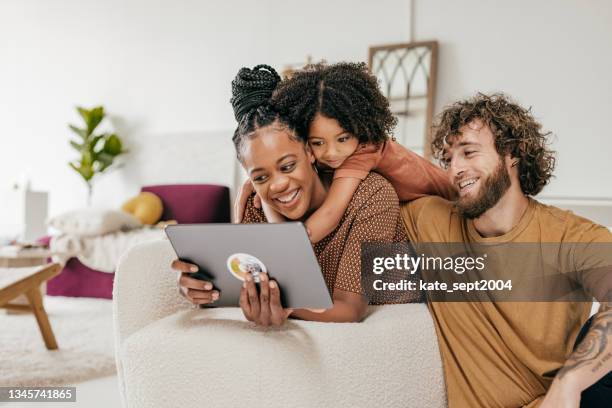 smiling parents and daughter at home watching online movie together - computador imagens e fotografias de stock