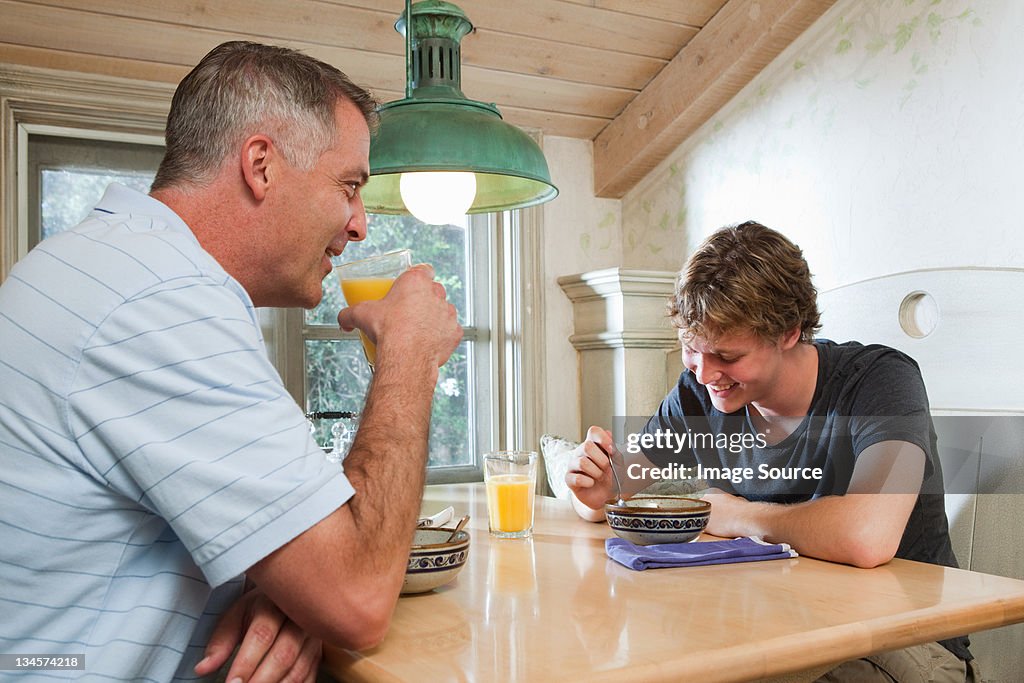 Mature man and son sitting together over breakfast