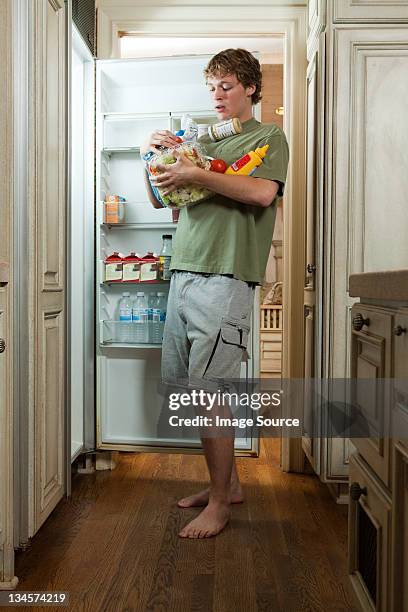 teenage boy taking food from fridge - excess photos et images de collection
