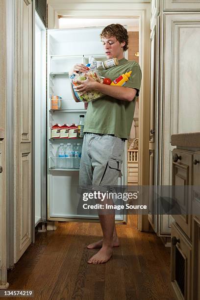 teenage boy taking food from fridge - high angle view stockfoto's en -beelden