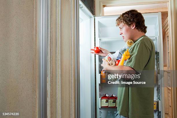 teenage boy taking food from fridge - over eating fotografías e imágenes de stock