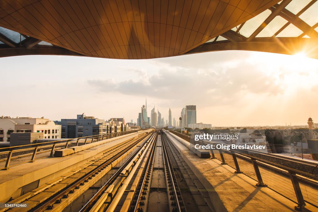 Driverless metro tracks in Dubai with futuristic skyline on background, UAE. Beautiful sunset light