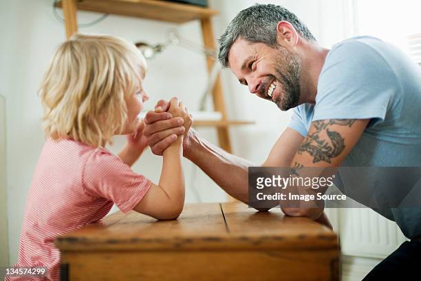 mid adult man arm wrestling with son - echar un pulso fotografías e imágenes de stock