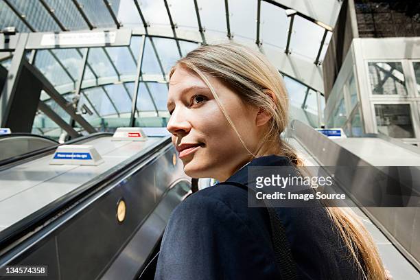 businesswoman on subway escalators - young woman looking over shoulder stock pictures, royalty-free photos & images