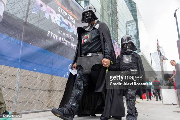 Sergio Santos and his son Andrew Santos both wearing Darth Vader costumes, walk outside Day 3 of New York Comic Con at Javits Center on October 09,...
