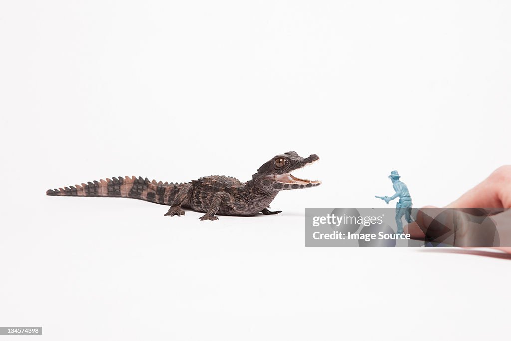 Small reptile attacking toy soldier