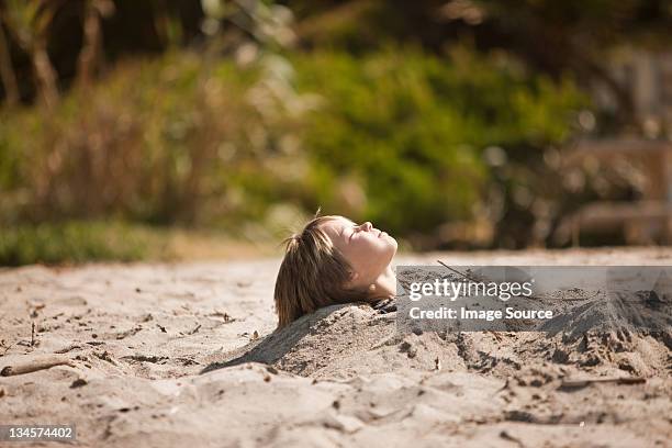 boy buried up to his neck in the sand - buried alive stockfoto's en -beelden