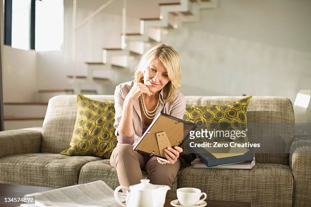 older woman admiring framed photos - minne bildbanksfoton och bilder
