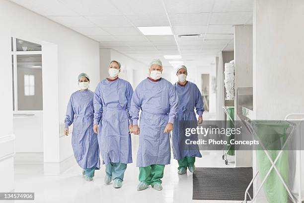 equipo quirúrgico caminando en el hospital - operating gown fotografías e imágenes de stock