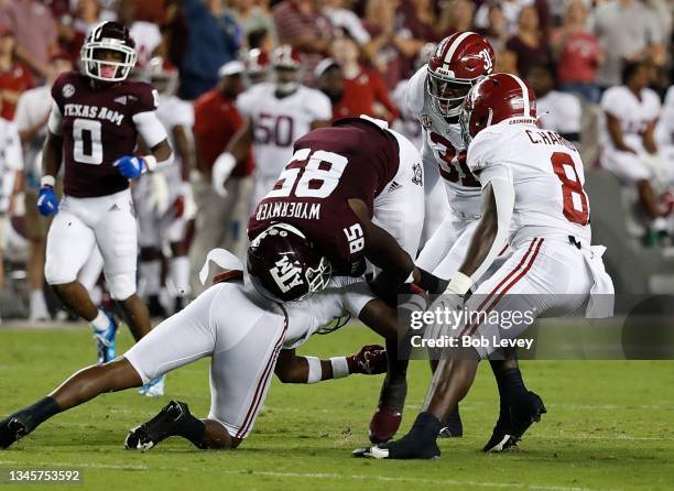 Jalen Wydermyer of the Texas A&M Aggies is tackled by Josh Jobe of the Alabama Crimson Tide with an assist from Christian Harris and Will Anderson...