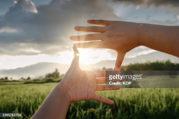 close-up of female hand outstretched touching scenic view of mountain range during sunset. - focus concept stock-fotos und bilder