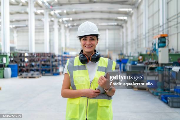 retrato de una ingeniera en la fábrica - orejeras fotografías e imágenes de stock