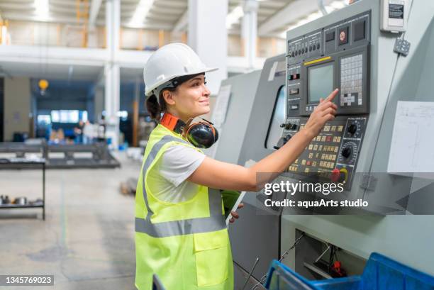 female engineer programming a cnc machine at factory - female factory stockfoto's en -beelden