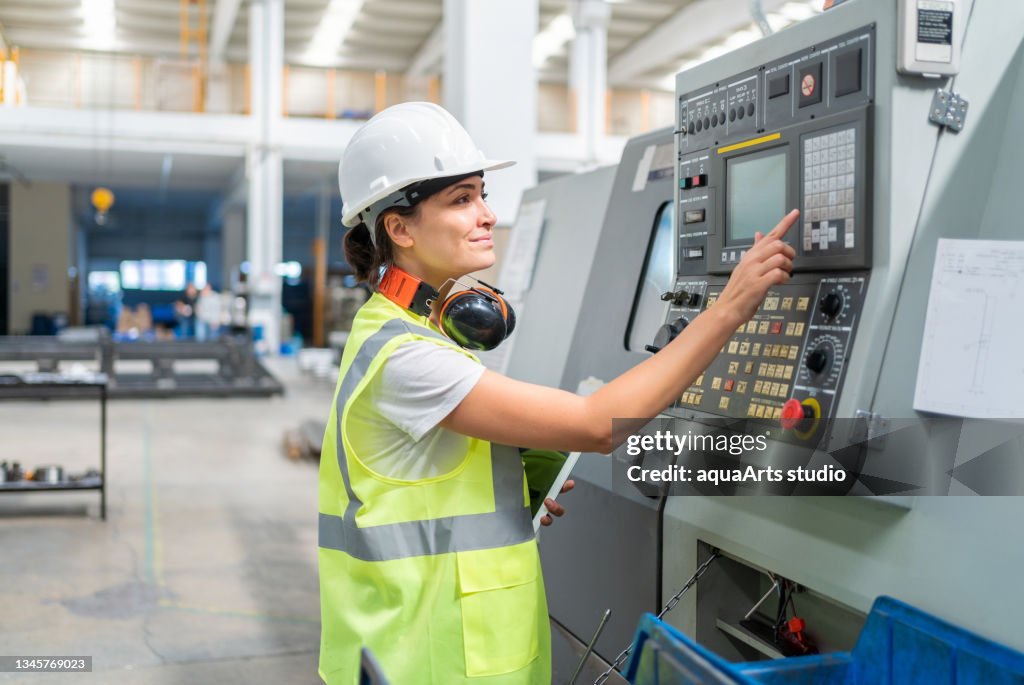 Female Engineer Programming A CNC Machine At Factory