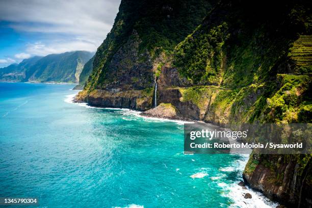 waterfall jumping into the ocean, madeira island - isla de madeira fotografías e imágenes de stock