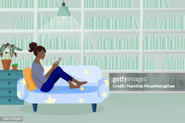 a library illustration concept shows a dark woman is reading a book and sitting on the warm sofa in the library that decorated like a home. - bookshelf foto e immagini stock