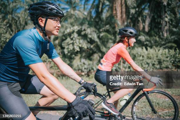 side view asian chinese couple cyclist enjoy road biking cycling during weekend morning together rural scene - 單車衫 個照片及圖片檔
