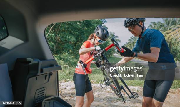 asian chinese couple unloading road bike from car trunk getting ready for cycling during weekend morning - unloading stock pictures, royalty-free photos & images