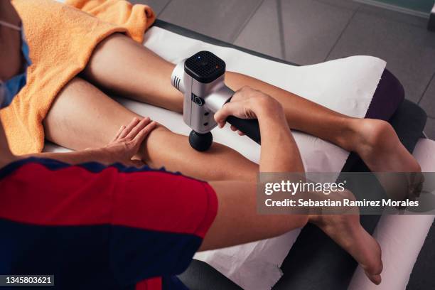 professional physiotherapist performs shock massage with sports pistol in gym medical office. concept of injury rehabilitation. close-up photography - massager stock pictures, royalty-free photos & images