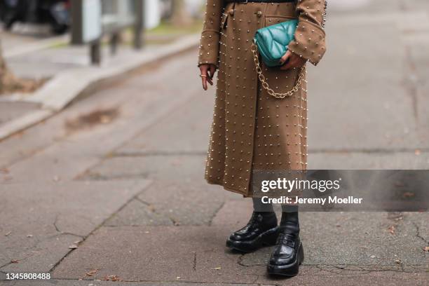 Bryan Boy wearing a brown coat and a blue bag outside Miu Miu Show on October 05, 2021 in Paris, France.