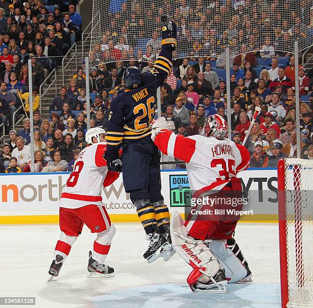 Thomas Vanek of the Buffalo Sabres jumps for a flying puck between Ian White and Jimmy Howard of the Detroit Red Wings at First Niagara Center on...