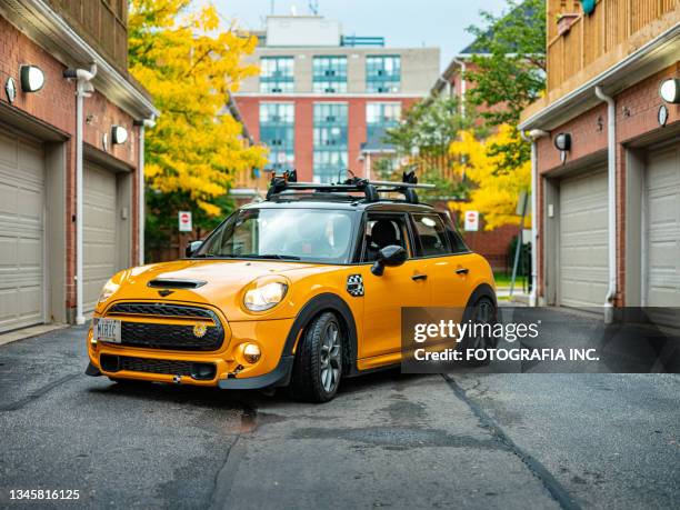 orange mini cooper en el barrio de la ciudad - mini cooper fotografías e imágenes de stock