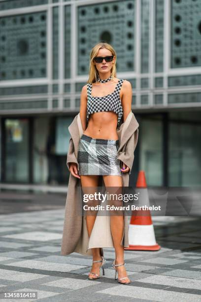 Paige Reifler wears black sunglasses from Saint Laurent, a black and silver rhinestones checkered pattern necklace, a black and silver rhinestones...