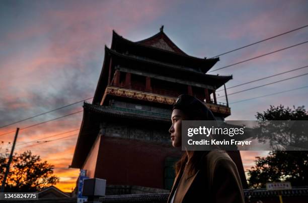 Woman stands near the Drum Tower at sunset in a traditional neighbourhood on October 10, 2021 in Beijing, China. The historical centre of China's...