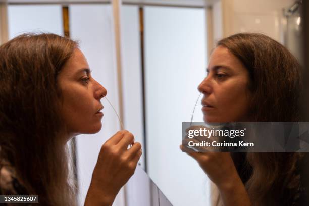 woman performing covid-19 antigen self-test via nasal swab at home - test autodiagnostico foto e immagini stock