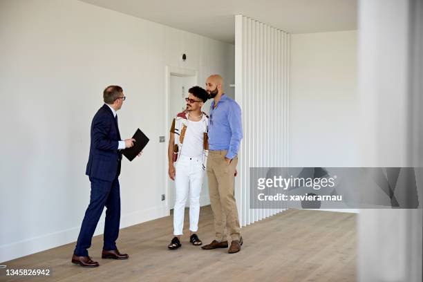 mid adult couple and real estate agent standing in apartment for sale - open house stock pictures, royalty-free photos & images