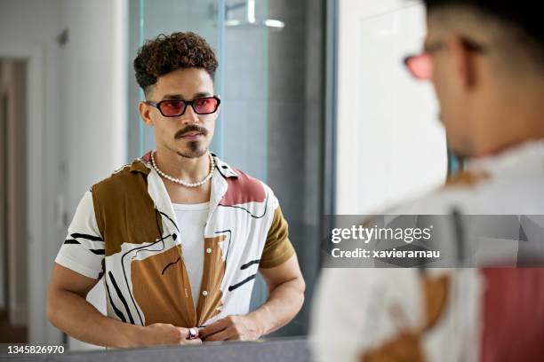 mid adult man buttoning shirt in bathroom mirror - buttoning shirt stockfoto's en -beelden