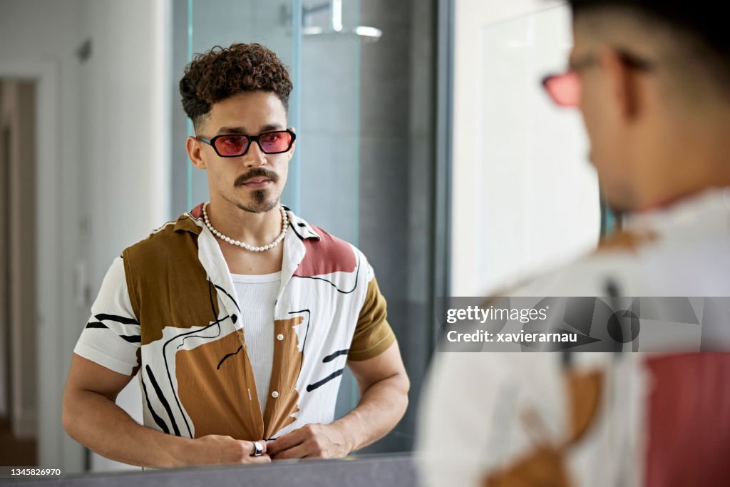 Mid Adult Man Buttoning Shirt in Bathroom Mirror
