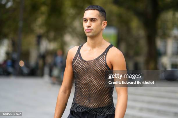 Guest wears silver earrings, a black mesh tank-top, black large flared pants, outside Ludovic de Saint Sernin, during Paris Fashion Week - Womenswear...