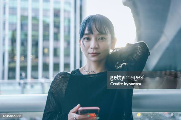 モバイルアプリを使用した美しいアジアの若い女性の肖像 - 若い女性 日本人 顔 ストックフォトと画像