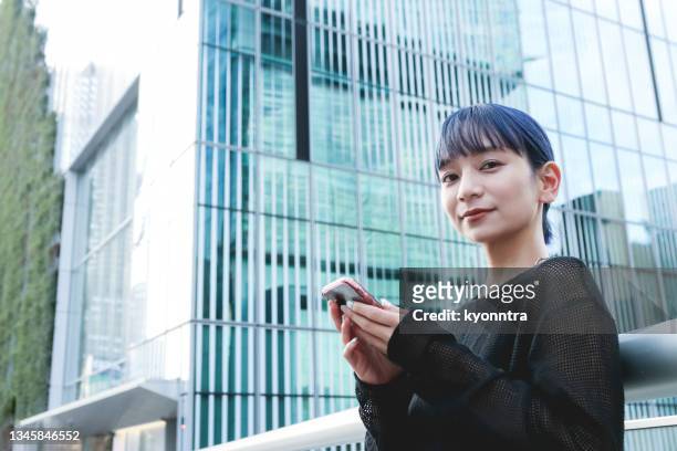 portrait of beautiful asian young woman using a mobile app - attitude youthful asian stockfoto's en -beelden