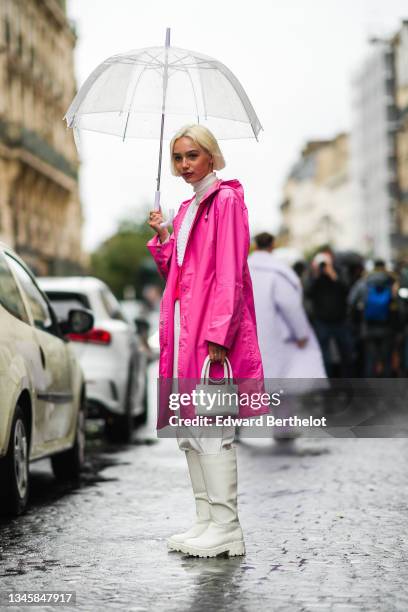 Guest wears a white transparent umbrella, a pearls necklace from Vivienne Westwood, a white latte turtleneck t-shirt, a half white braided wool and...