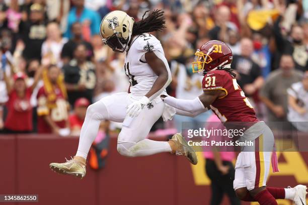 Alvin Kamara of the New Orleans Saints scores a touchdown as Kamren Curl of the Washington Football Team defends during the first half at FedExField...
