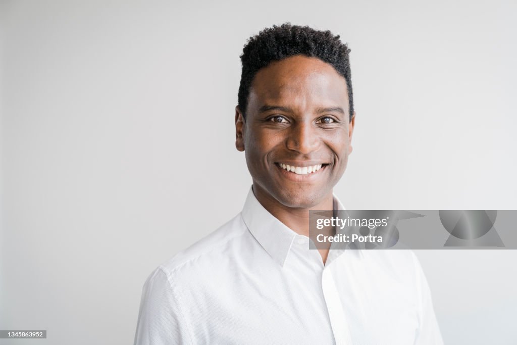 Portrait of smiling businessman against gray wall