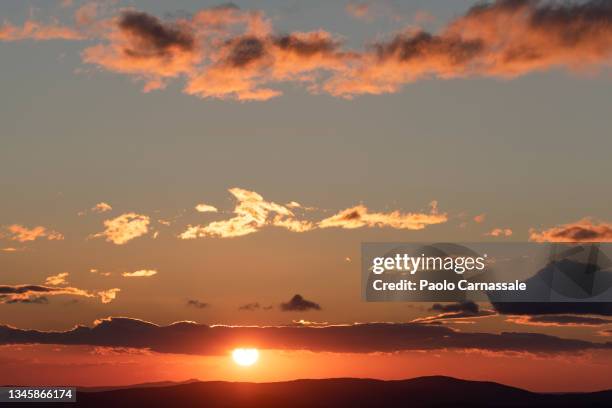 sun setting over the mountain range - cielo romantico foto e immagini stock