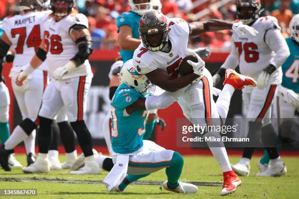 Leonard Fournette of the Tampa Bay Buccaneers is tackled by Jason McCourty of the Miami Dolphins during the first half at Raymond James Stadium on...