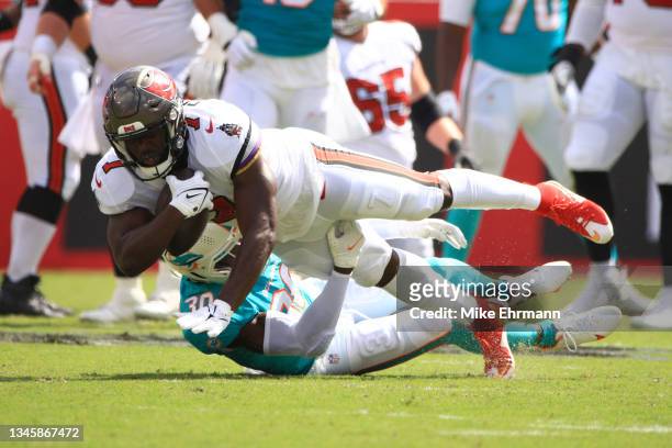 Leonard Fournette of the Tampa Bay Buccaneers is tackled by Jason McCourty of the Miami Dolphins during the first half at Raymond James Stadium on...