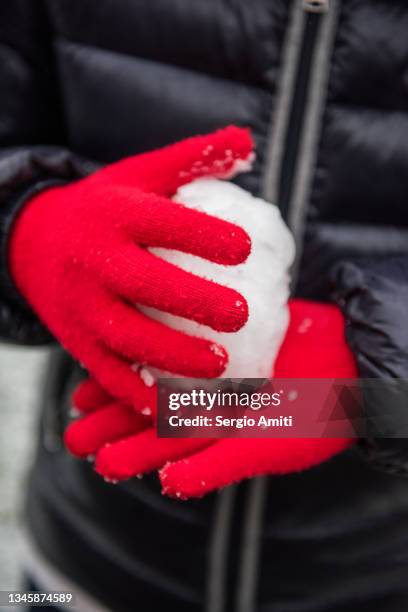 red knitted gloves making a snow ball - red glove stock pictures, royalty-free photos & images